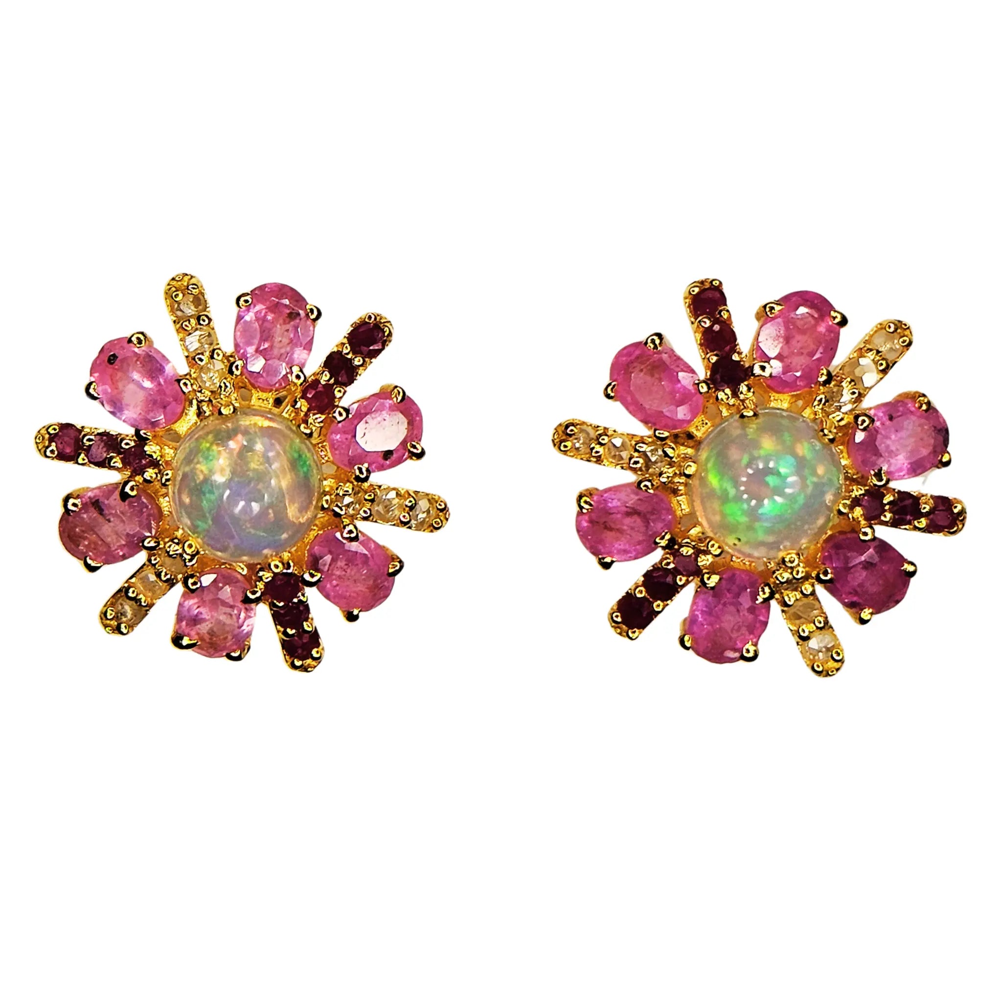 Pair of gold earrings with pink sapphire gemstones and a central opal stone on a white background