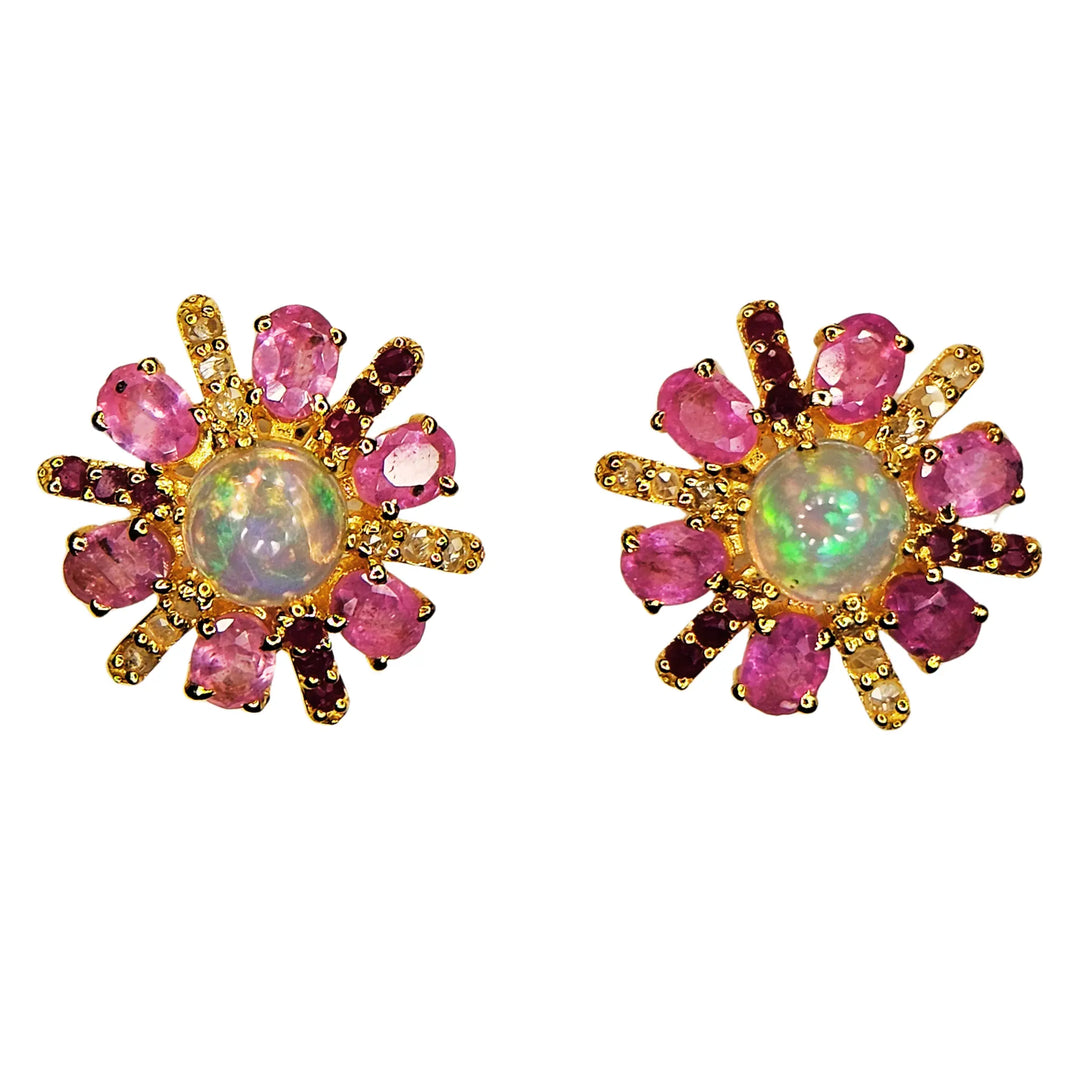 Pair of gold earrings with pink sapphire gemstones and a central opal stone on a white background
