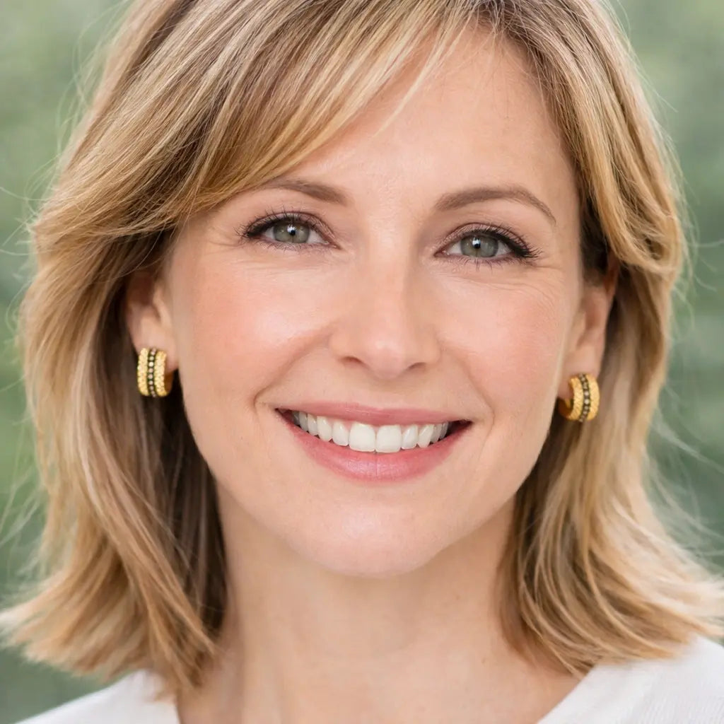 Woman with blonde hair and gold ribbon earrings against a blurred green background